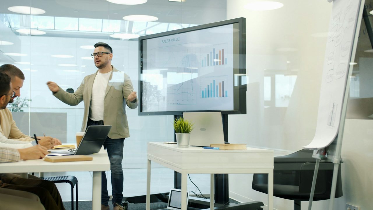 Persona presentando datos a su equipo en una pantalla