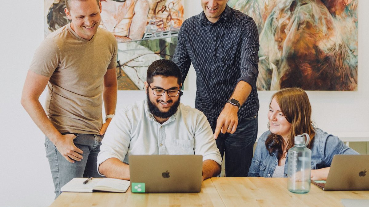 Equipo sonriendo alrededor de una computadora